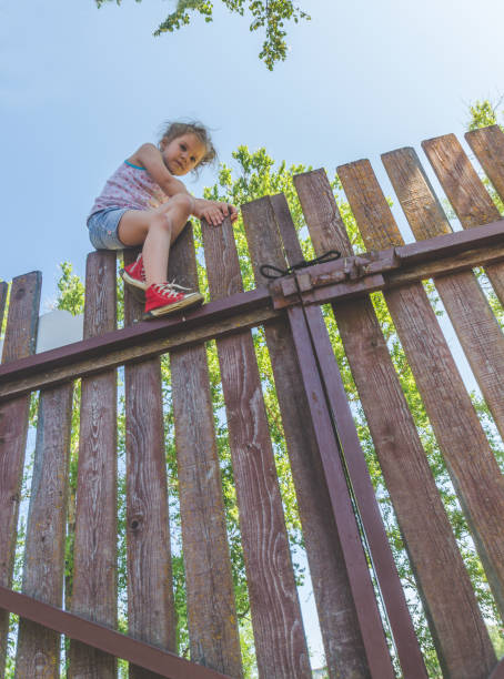 istock girl climbs the fence on a summer day 1005428766