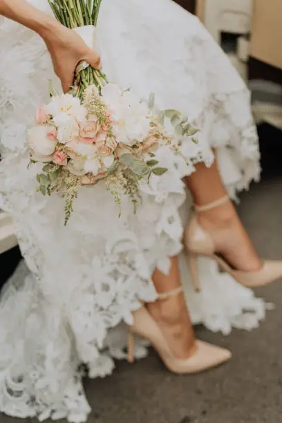 Photo of bride with a bouquet from car
