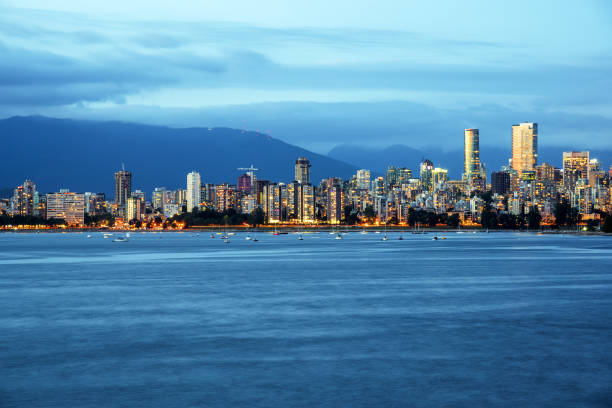 Vancouver Skyline at Dusk on a Cloudy Summer Day English Bay and Vancouver Downtown under a Storming Sky at Dusk. Some Mountains are Visible in Background. Vancouver, BC, Canada. beach english bay vancouver skyline stock pictures, royalty-free photos & images