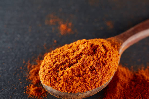 istock Texture background. Red chilli pepper powder mixed with wooden spoon. Top view 1005459990