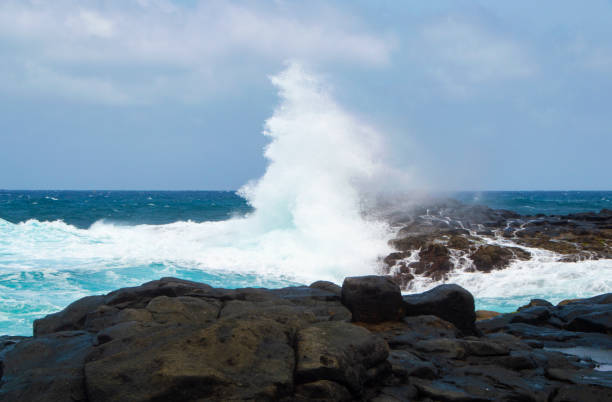 istock Great wave splash on the rocky beach daytime 1005460136