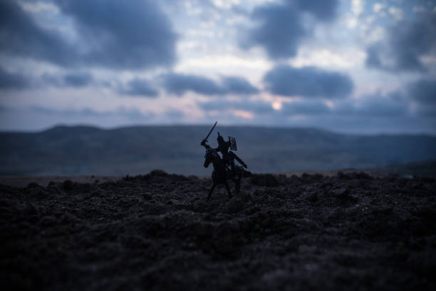 istock Medieval battle scene with cavalry and infantry. Silhouettes of figures as separate objects, fight between warriors on sunset foggy background. 1005463442