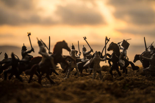 istock Medieval battle scene with cavalry and infantry. Silhouettes of figures as separate objects, fight between warriors on sunset foggy background. 1005463468