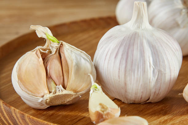 istock Garlic close up on wooden plate on rustic background, shallow depth of field, selective focus, macro 1005470710