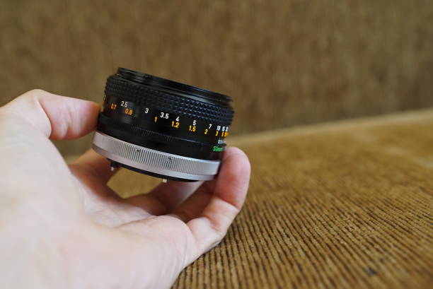 istock Male hand holding vintage camera lens 1005479932