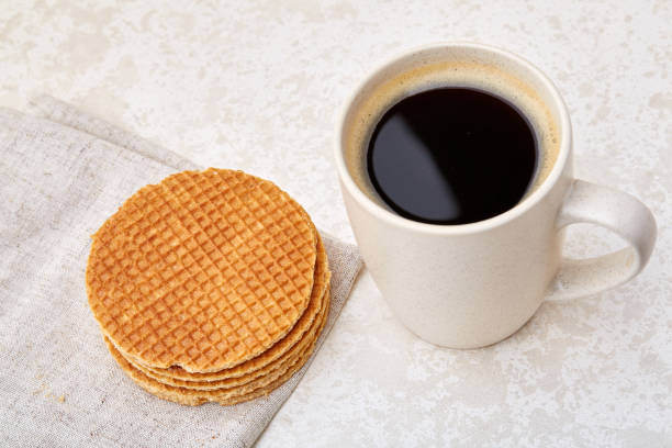 istock Close-up white cup of coffee with waffles on white background, top view 1005480830