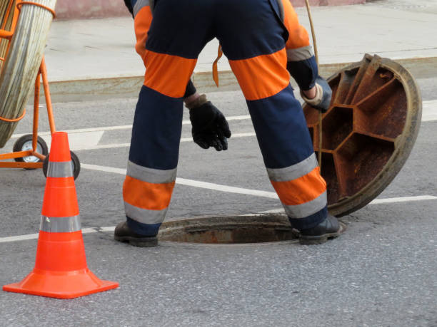 istock Worker in uniform stand over the open sewer hatch 1005490092