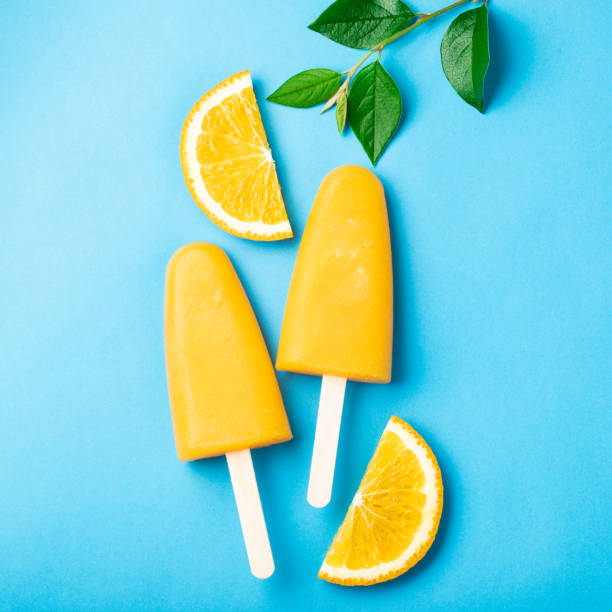 istock Orange popsicles with juice on a blue background. Ice pops, flat lay, top view 1005495542