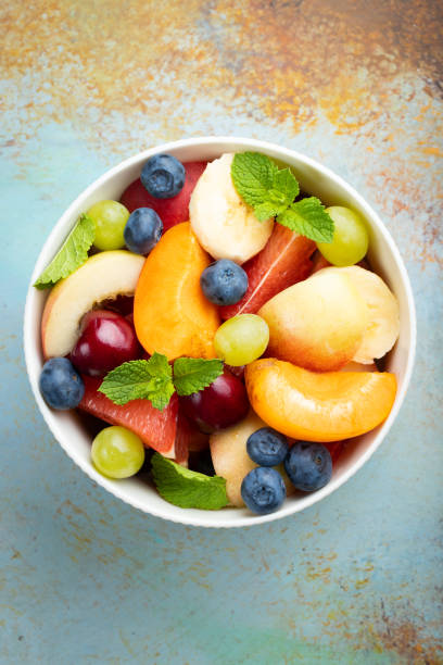 istock Bowl of healthy fresh fruit salad on a blue rusty background. Top view 1005495610