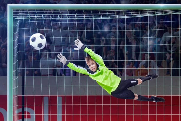 istock goalkeeper jumping for the ball on a crowded stadium 1005507918
