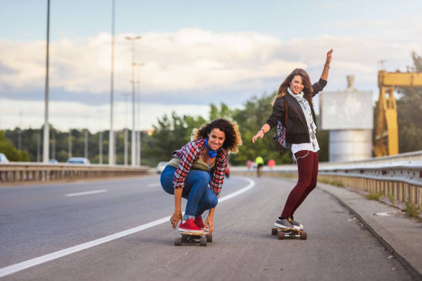 istock Skateboard girls riding longboards down the road 1005517690
