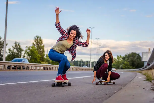 Skateboard girls riding long boards down the road