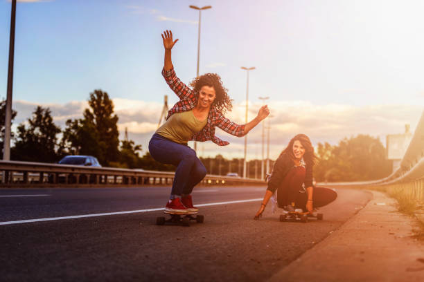 istock Skateboard girls riding longboards down the road 1005519922