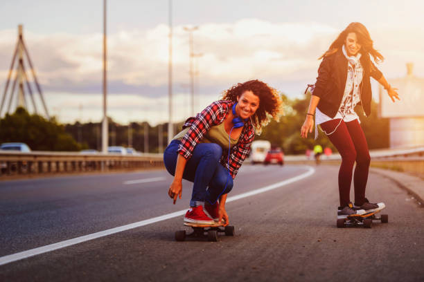 istock Skateboard girls riding longboards down the road 1005519924