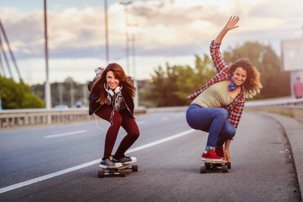 istock Skateboard girls riding longboards down the road 1005520230