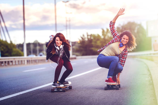 istock Skateboard girls riding longboards down the road 1005520236