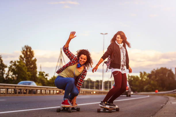istock Skateboard girls riding longboards down the road 1005520548