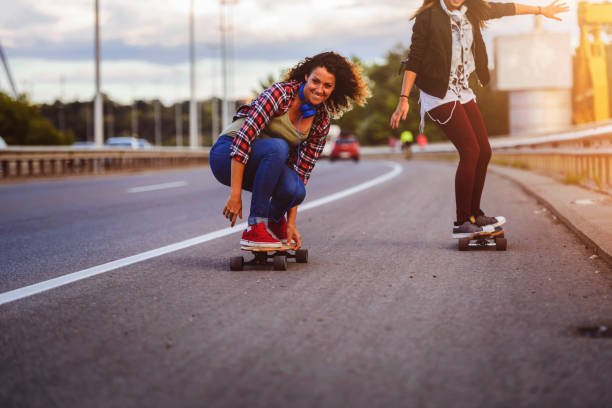 istock Skateboard girls riding longboards down the road 1005520582