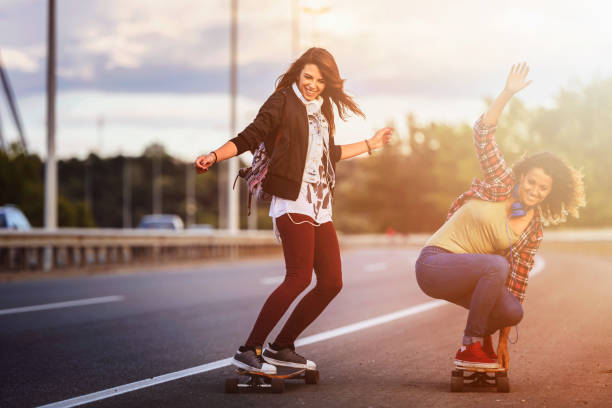 istock Skateboard girls riding longboards down the road 1005520610