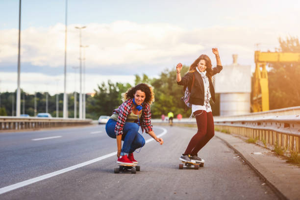 istock Skateboard girls riding longboards down the road 1005520808