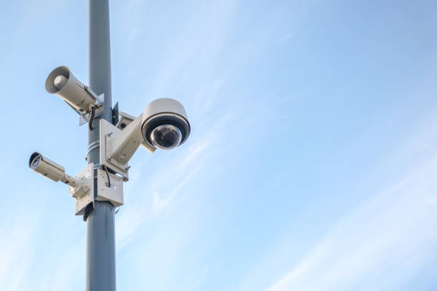 istock Modern surveillance cameras on a pole against a blue sky. 1005523582