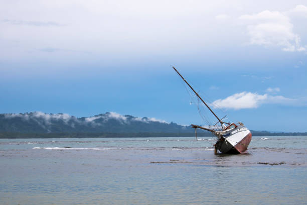 Sunrise in pink and blue over ocean with one tilted boat in foreground