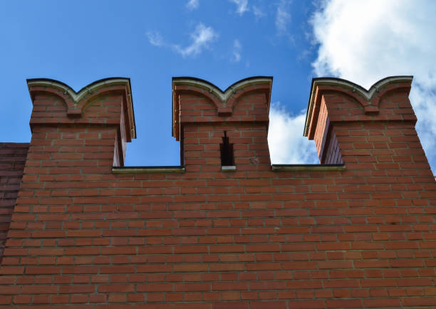 istock Stone medieval wall against a cloudy blue sky. Red Kremlin wall in Moscow, a historical landmark of Russia. Battlements of the wall 1005529460