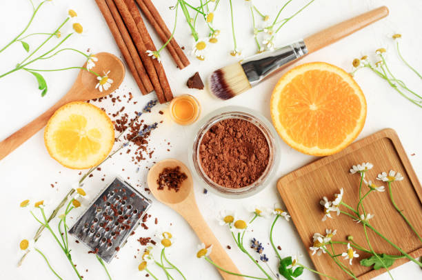 Preparing Homemade skin care treatment products, set of different ingredients viewed above white table. Cocoa powder, orange, chamomile, cinnamon. Organic cosmetics. botanical spa treatment stock pictures, royalty-free photos & images