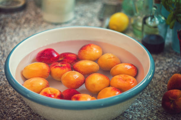 Young woman cleaning and washing fresh apricots for making homemade jam