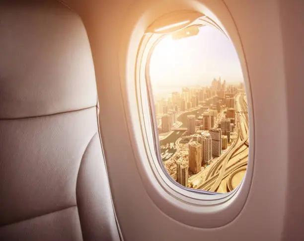 Airplane interior with window view of Dubai city, UAE. Concept of travel and air transportation