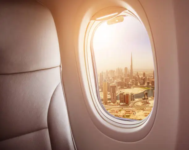 Airplane interior with window view of Dubai city, UAE. Concept of travel and air transportation