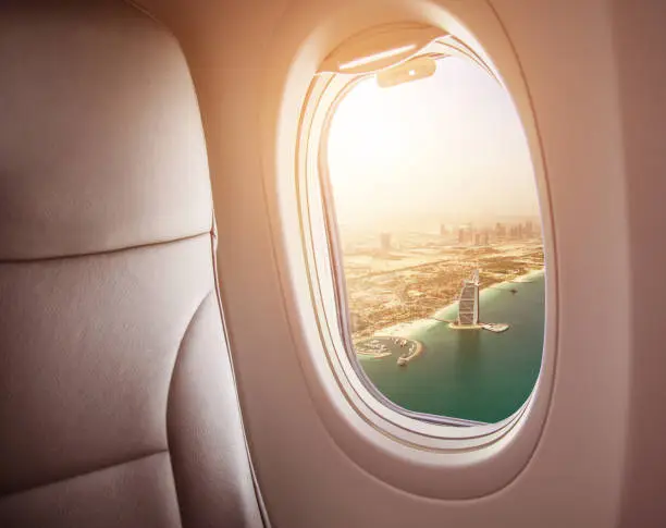 Airplane interior with window view of Dubai city, UAE. Concept of travel and air transportation