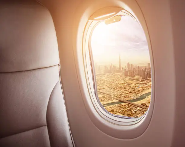 Airplane interior with window view of Dubai city, UAE. Concept of travel and air transportation