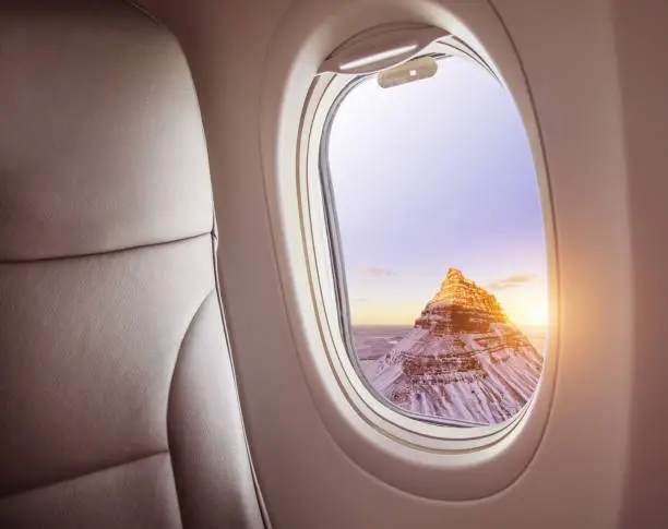 Airplane interior with window view of Kirkjufell mountain, Iceland. Concept of travel and air transportation