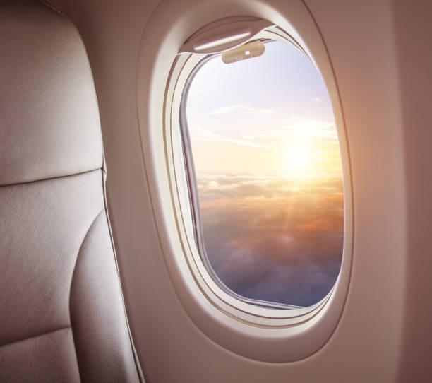 istock Airplane interior with window view of sunset above clouds. 1005590694