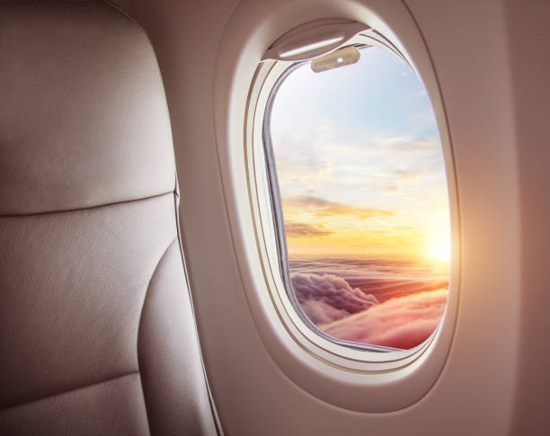 istock Airplane interior with window view of sunset above clouds. 1005592098