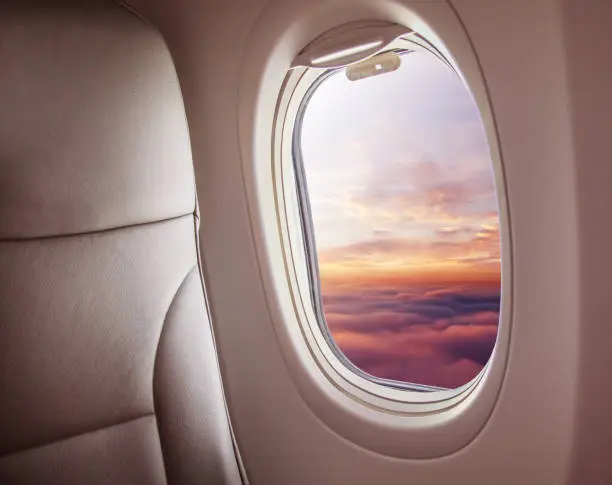 Airplane interior with window view of sunset above clouds. Concept of travel and air transportation