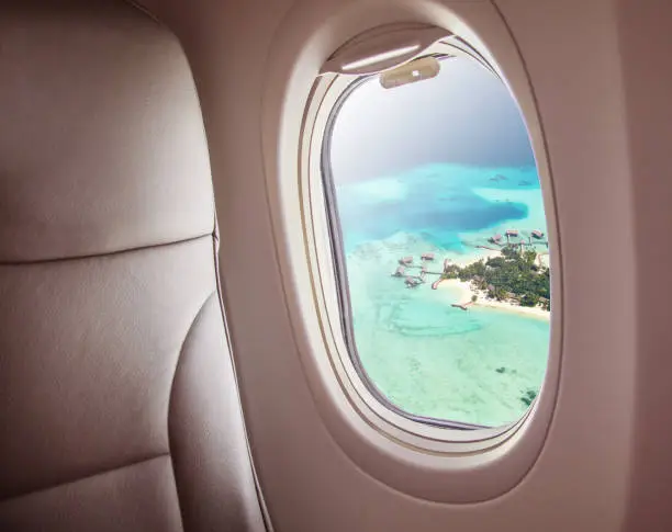 Airplane interior with window view of Maldives island. Concept of travel and air transportation