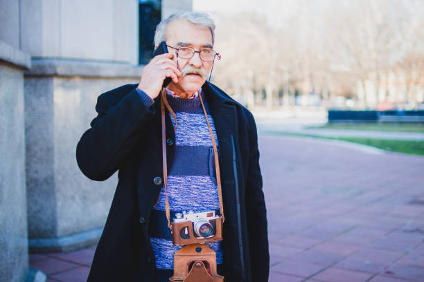 istock Older man with smart phone and retro camera 1005596182