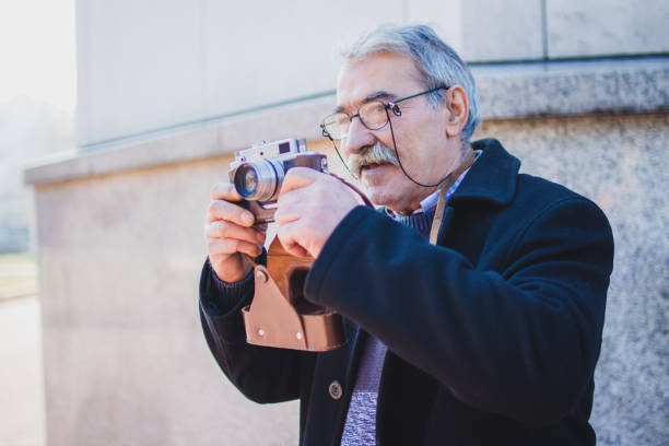 istock Senior Adult Man with Old Fashioned Camera 1005598996