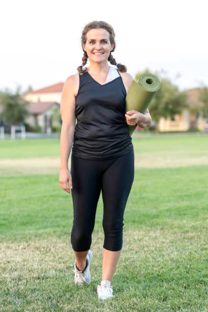 istock mature woman walking holding her exercise mat 1005599726