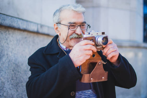 istock Senior Adult Man with Old Fashioned Camera 1005599792