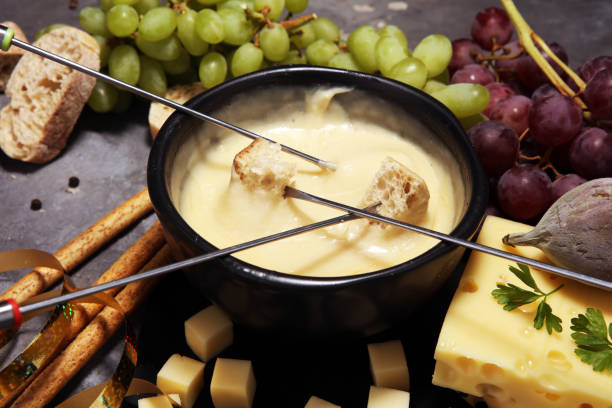 istock Gourmet Swiss fondue dinner on a winter evening with assorted cheeses on a board alongside a heated pot of cheese fondue 1005600178