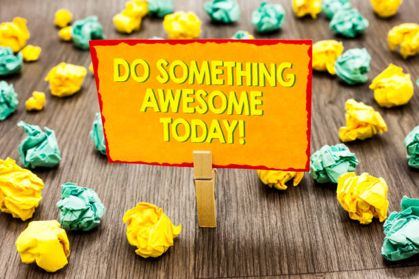 Handwriting text Do Something Awesome Today. Concept meaning Make an incredible action motivate yourself Paperclip hold written yellow page colorful paper lobs laid on wooden floor.