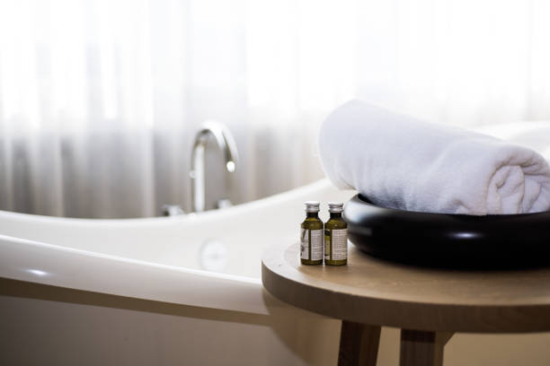 White towel and massage bath oil on table in bathroom.