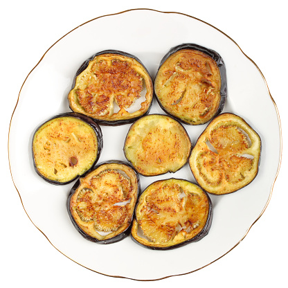 Sliced roasted eggplants in a white porcelain plate isolated on a white background