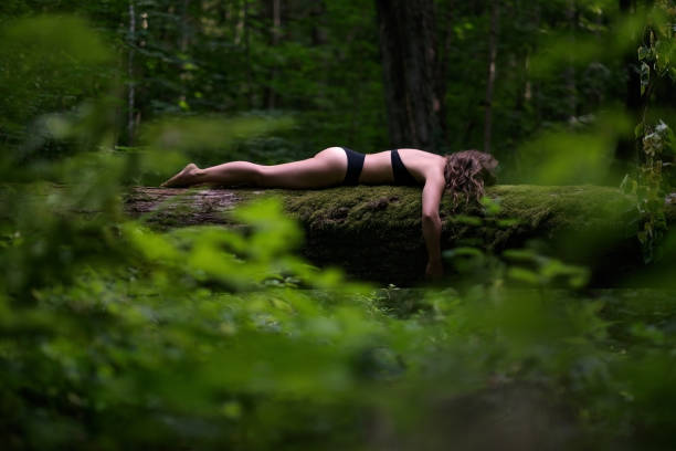 istock European woman on tree trunk sleeping in dark forest. 1005618882
