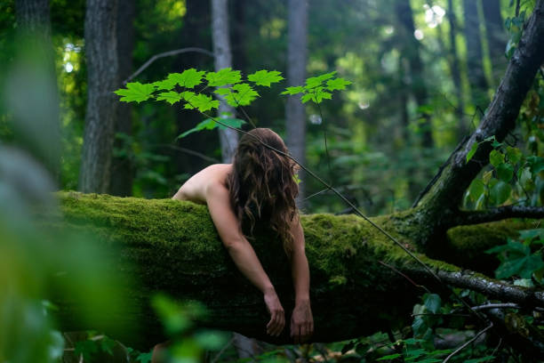European woman on tree trunk sleeping in dark forest.