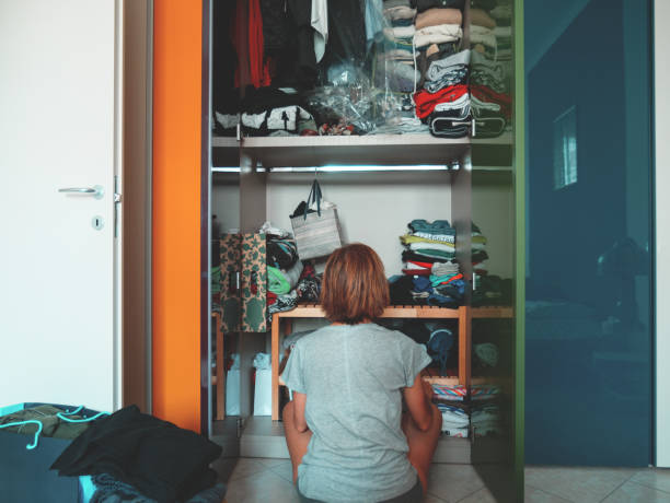 woman looking at wardrobe, home interior, desperate housewife, cleaning home, rear view sitting, toned vintage style. - aspirations choice choosing women imagens e fotografias de stock