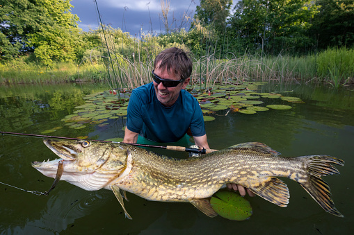 Happy angler with pike fishing trophy